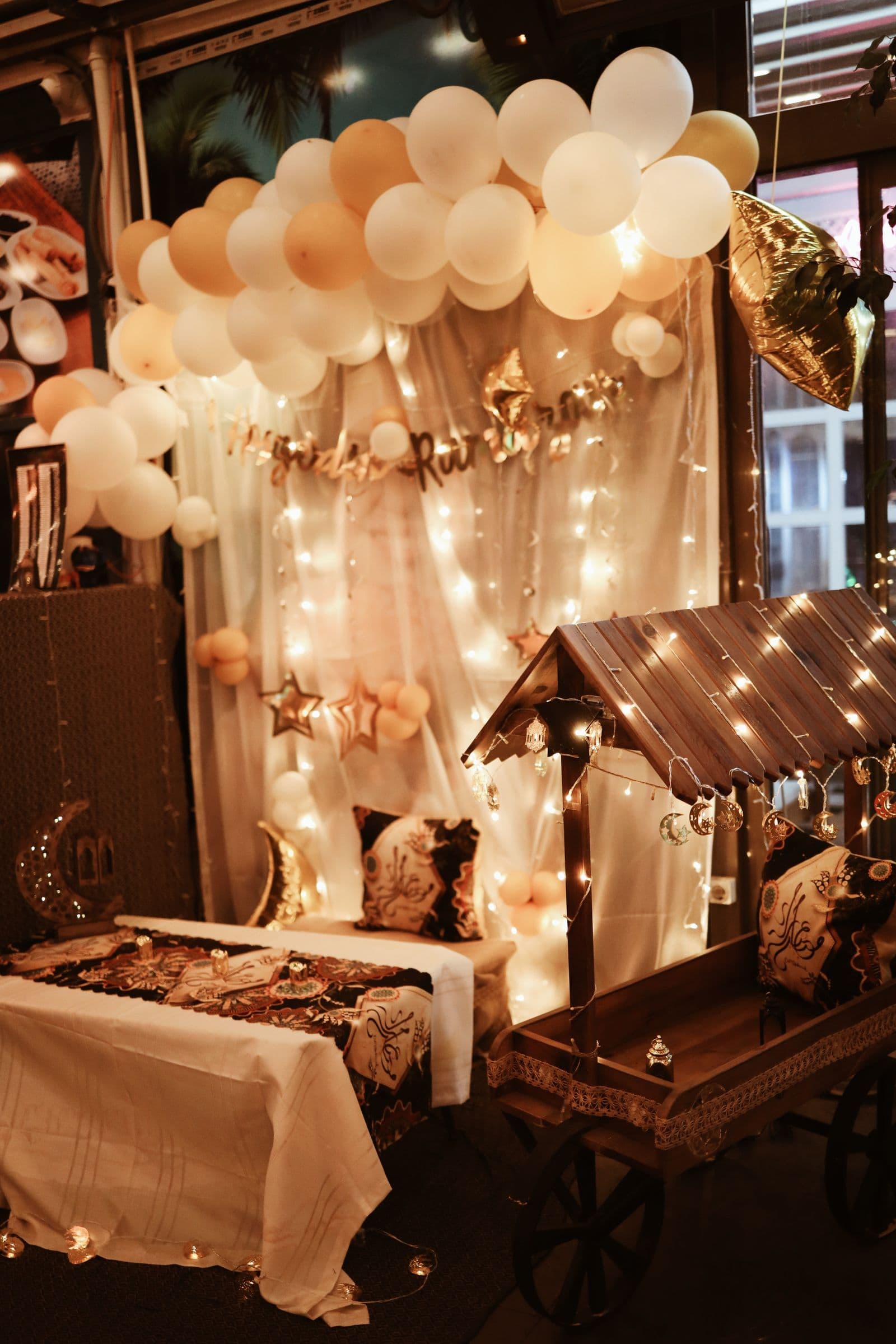 Softly lit balloon and fairy-light styling creating a warm, layered celebration setting
