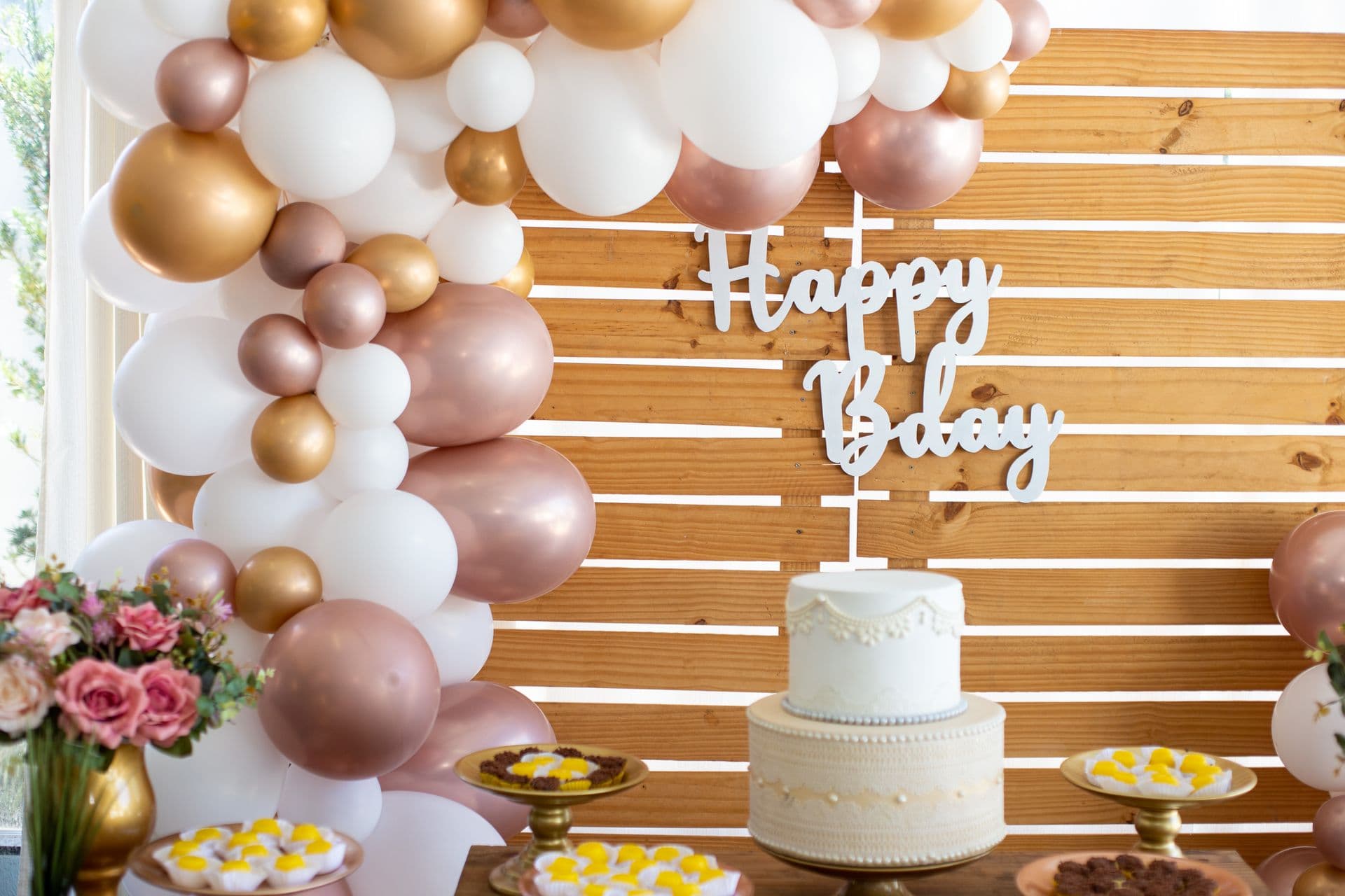 Elegant cream and rose-gold birthday balloon backdrop with cake