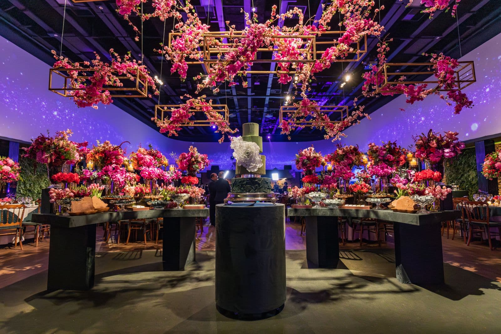 Dramatic suspended pink floral installations over an elegantly styled luxury event reception